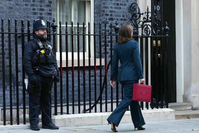 Eine Frau läuft mit einem roten Koffer in der Hand an einem Polizisten vorbei