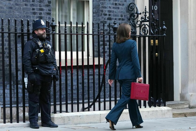 Eine Frau läuft mit einem roten Koffer in der Hand an einem Polizisten vorbei