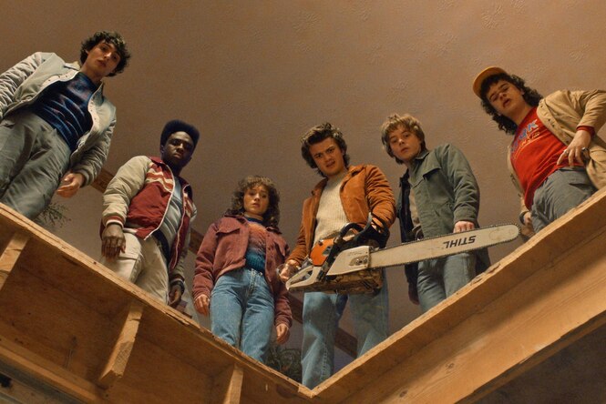 Personen stehen an einem Treppengeländer, einer hält eine Kettensäge in den Händen