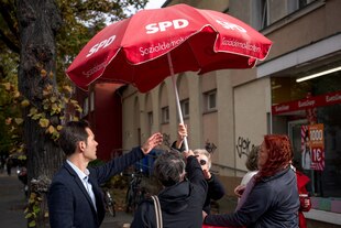 Menschen mühen sich beim Aufstellen eines SPD-Schirms