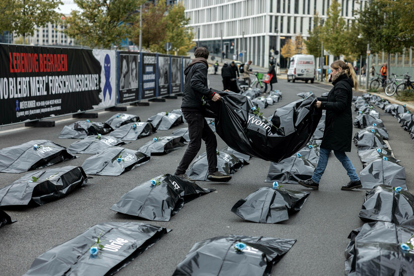 Protestaktion mit Leichensäcken auf einer Straße.