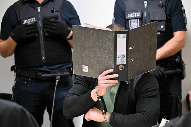 Eine Person hält sich einen Aktenordner vor das Gesicht