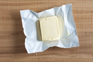 Ein Stück Butter liegt auf dem Tisch, die Verpackung ist offen