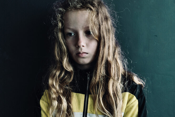 Ein traurig guckendes Mädchen mit verschränkten Armen