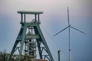 Der ehemalige Förderturm aus grünem Stahl von Schacht Konrad - im Hintergrund steht ein Windrad