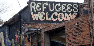 Eine Häuserfront, darauf der Schriftzug „Refugees welcome", Flüchtlinge willkommen