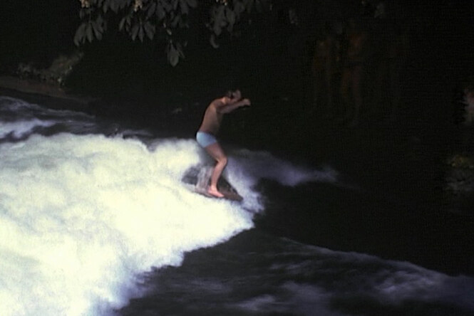 Historische unscharfe Aufnahme von einem Surfer auf einer Flußwelle