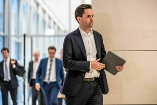 Johannes Winkel (CDU) mit ernster Miene und offenem Jackett im Bundestag, er trägt ein Labtop in der Hand