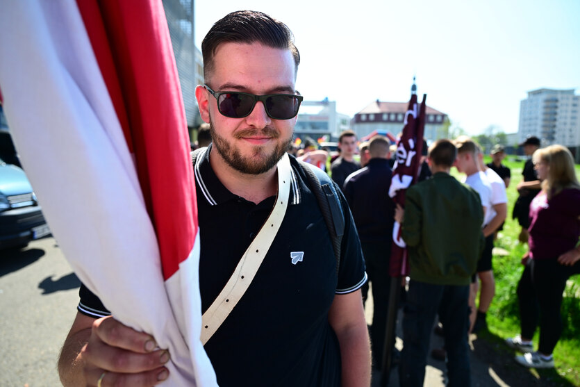 Ein Mann mit Scheitel und Sonnenbrille hält eine Fahne in der Hand.
