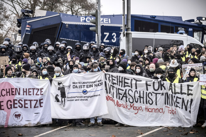 Demonstrant:innen mit Transparenten vor einem Wasserwerfer.