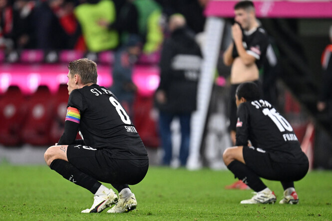 Zwei enttäuschte Spieler in der Hocke auf dem Rasen nach dem Schlusspfiff