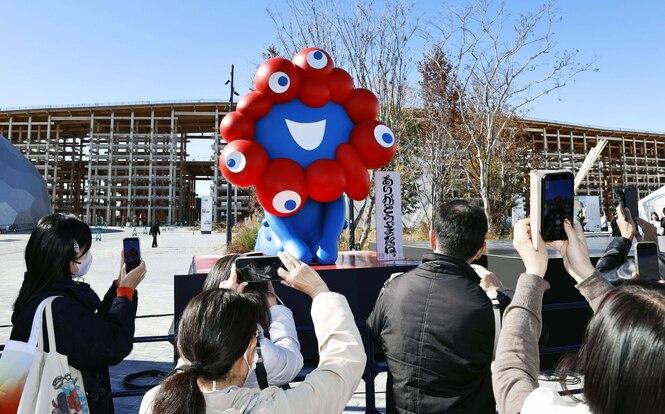 Menschen und ein blau-rotes Gebilde vor einem großen Gebäude