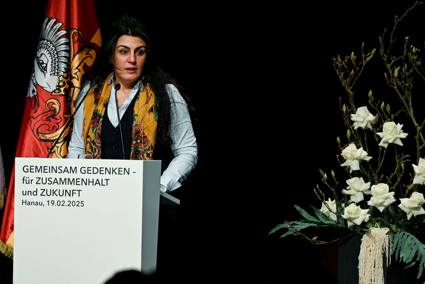 Eine Frau steht an einem Rednerpult und spricht ins Mikrofon