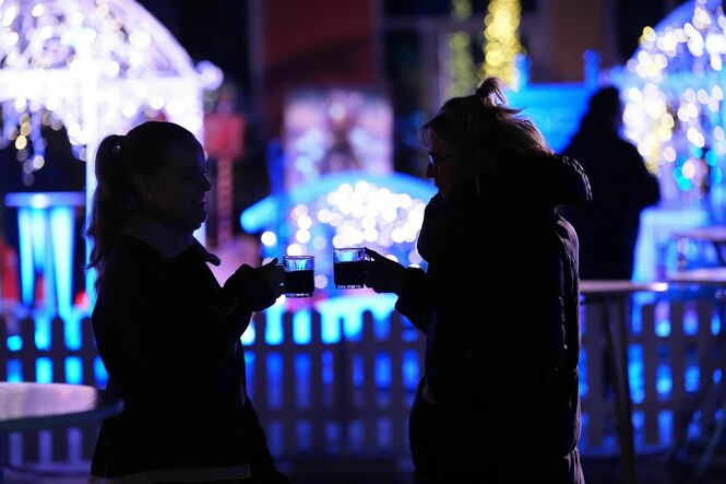 Zwei Weihnachtsmarktbesucherinnen unterhalten sich bei einem Glühwein