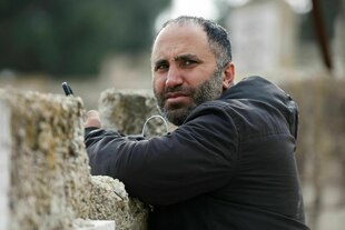 Ein Mann lehnt sich an eine Mauer