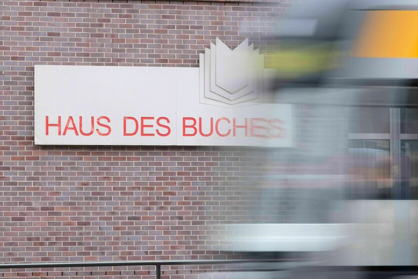 Eine Straßenbahn fährt am Haus des Buches vorbei, an dem das Logo angebracht ist