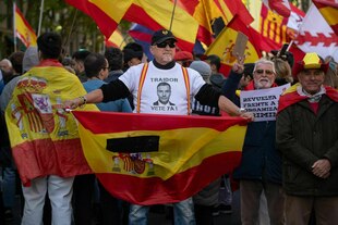 Bei dem Protest am Sonntag trägt ein von spanischen Flaggen umgebener Demonstrant ein T-Shirt mit der Aufschrift: 