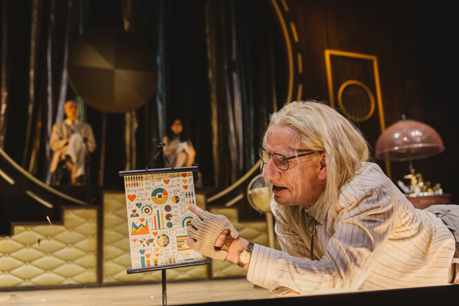 Ein Schauspieler zeigt etwas auf einer Tafel