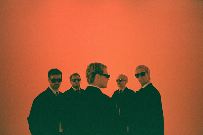 Fünf Personen in Schwarz vor rotem Licht