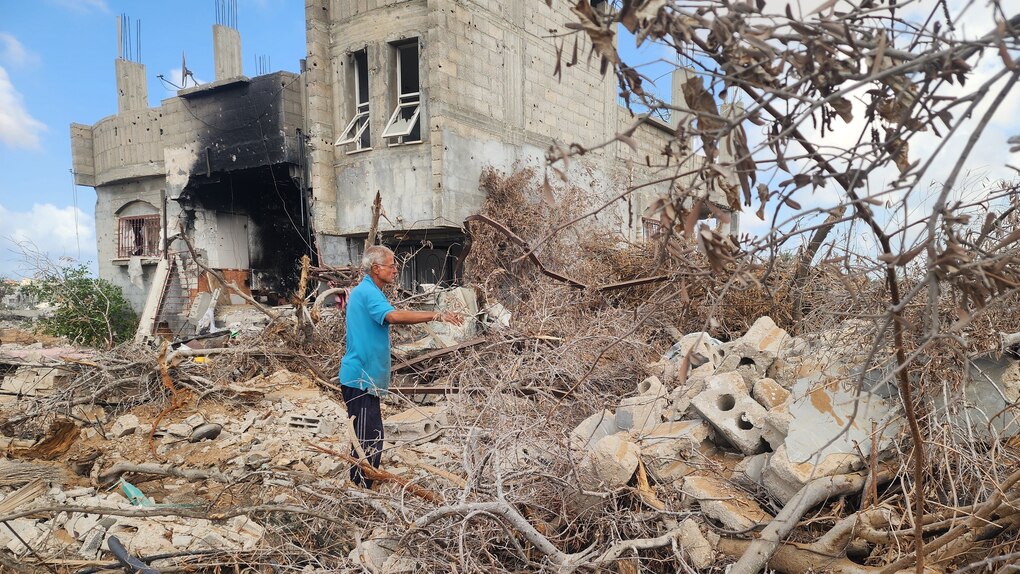 Tahseen Al-Abadla zwischen zerstörten Olivenbäumen und einem zerstörten Haus.