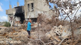 Tahseen Al-Abadla zwischen zerstörten Olivenbäumen und einem zerstörten Haus.