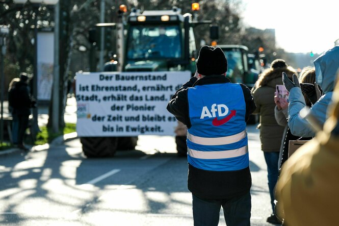 Mann mit AfD-Weste fotografiert mit Handy einen Traktor bei einem Bauernprotest