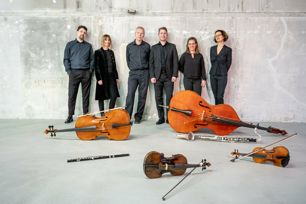 Die Musiker des Ensemble KNM stehen vor ihren auf dem Boden verteilten Instrumenten.