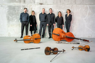 Die Musiker des Ensemble KNM stehen vor ihren auf dem Boden verteilten Instrumenten.