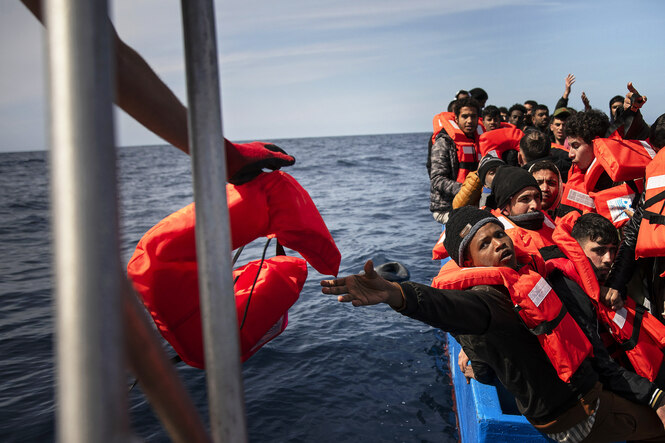 Menschen werden aus einem überfüllten Holzboot gerettet, das im Mittelmeer in Seenot geraten ist