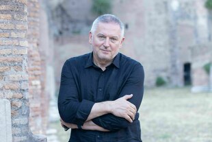 Ein Mann mit verschränkten Armen schaut in die Kamera