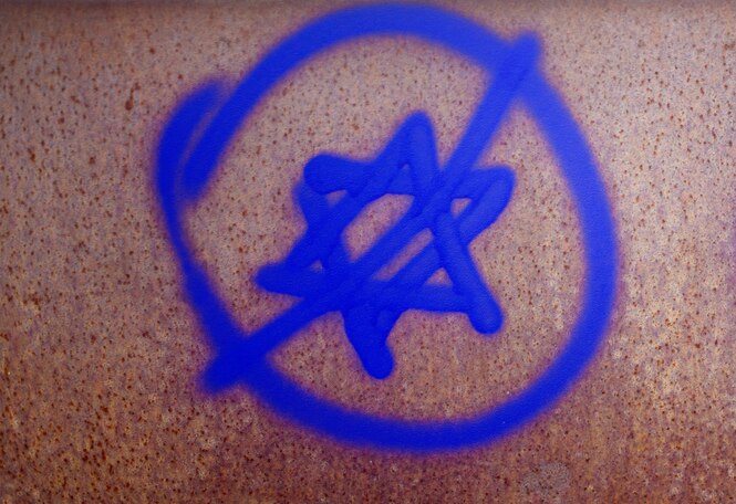 Ein Graffiti in blauer Farbe, das einen durchgestrichenen Davidstern zeigt