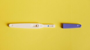 Schwangerschaftstestsstreifen mit positivem ERgebnis vor gelbem Hintergrund