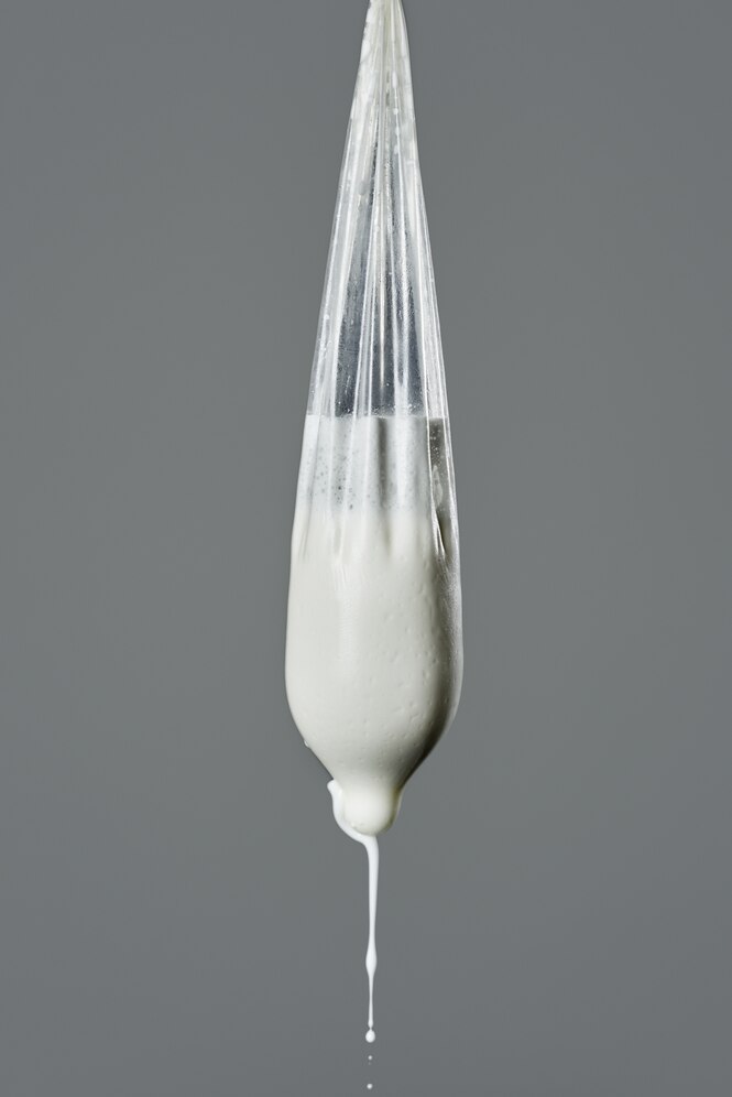 Ein Kondom ist prall gefüllt mit Milch, so dass es aussieht wie eine weibliche Brust