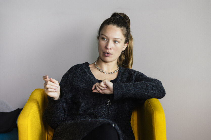 Portrait von Martyna Linartas, die auf einem gelben Stuhl sitzt