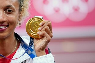 Sportlerin hält eine Goldmedaille in die Kamera