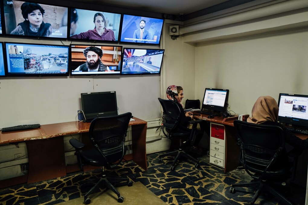 Zwei Frauen sitzen bei Tolo News in Kabul neben einer Wand mit Bildschirmen