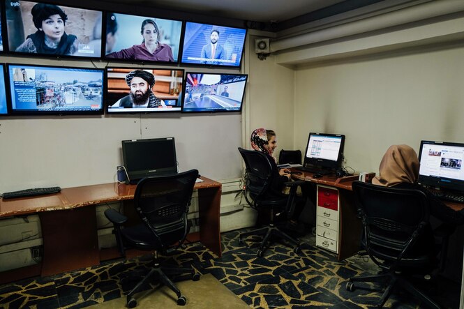 Zwei Frauen sitzen bei Tolo News in Kabul neben einer Wand mit Bildschirmen