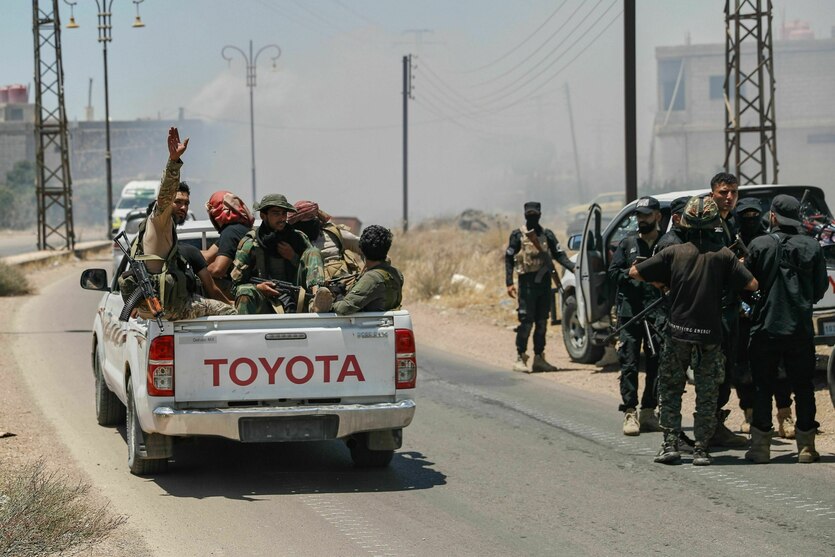Soldaten auf einem Laster fahren eine Straße entlang