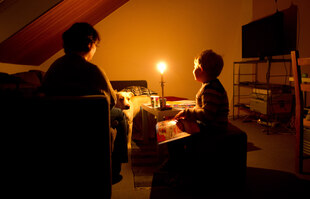 Eine Mutter und ihr Sohn sitzen im Schein einer Kerze in einem Zimmer