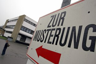 Wegweiser mit Aufschrift "zur Musterung" vor einem Gebäude