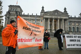 Demonstranten mit Bannern vorm Reichstagsgebäude
