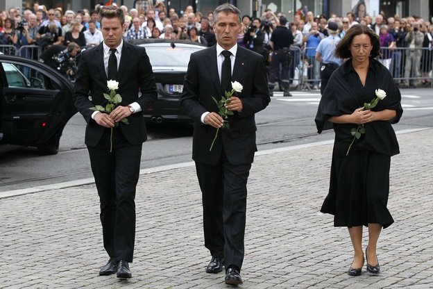 Menschen in schwarz gekleidet mit einer weißen Rose in der Hand auf einer Straße