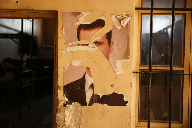 ein beschädigtes Foto von al Assad an einer Wand