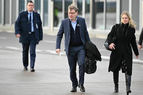 Johann Wadephul windzerzaust mit Aktentasche, daneben seine Sprecherin Kathrin Deschauer