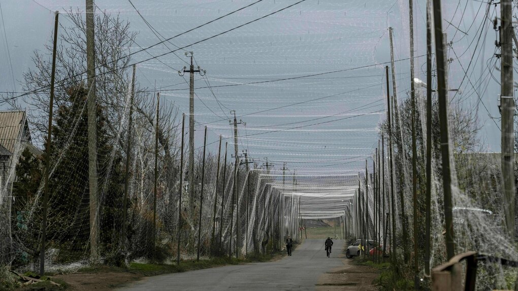 Über einer Landstraße ist ein Radfahrer unterwegs - über der Straße sind dichte Netze gespannt