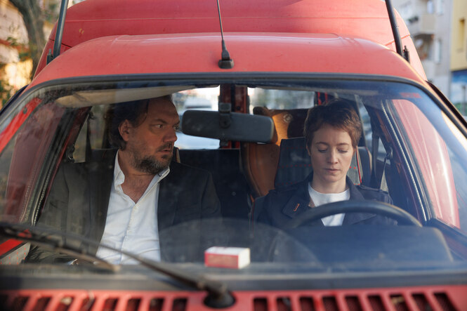 Charly Hübner und Leonie Benesch sitzen in den Rollen als Vater und Tochter in einem roten Kleintransporter.