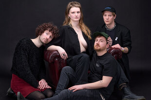 Die MusikerInnen sitzen vor einer schwarzen Wand