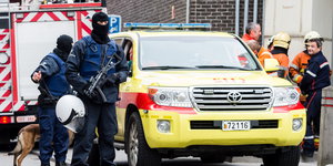 Sicherheitskräfte mit Maschinenpistolen und ein Polizeifahrzeug