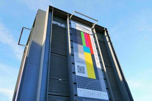 Ein buntes Plakat hängt an einem Hochhaus