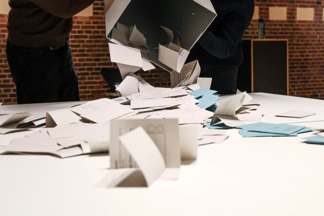Eine Wahlurne mit den Stimmzetteln der Stichwahl um den Kieler Oberbürgermeisterposten wird auf einen Tisch ausgeleert zur Auszählung